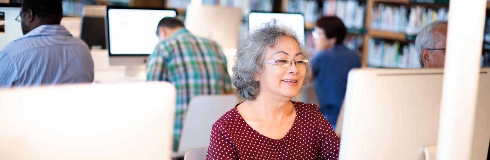 wo,am with gray hair at a desk with a computer in a library setting