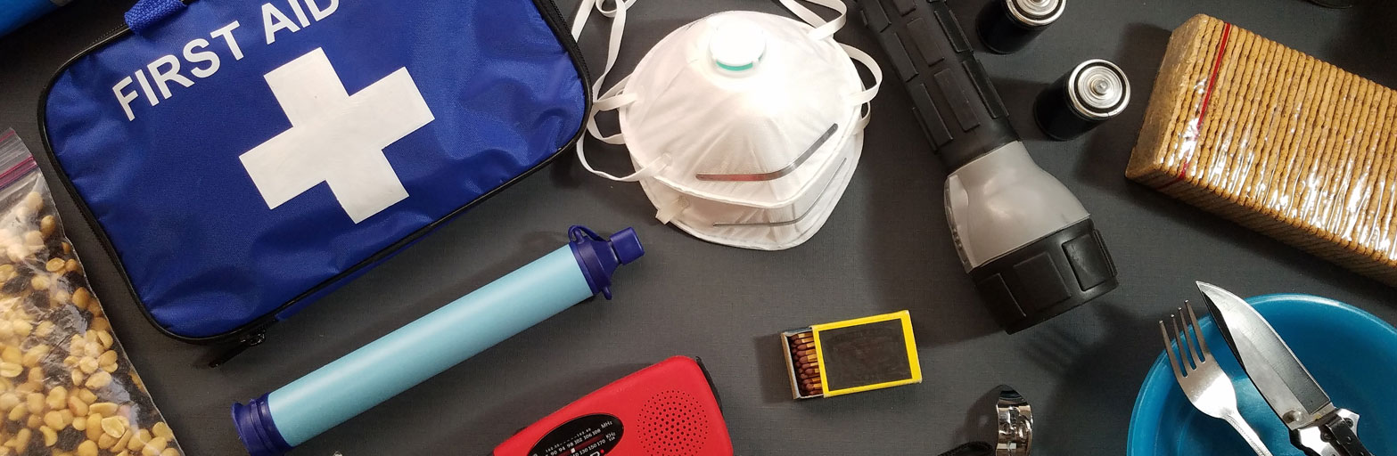 disaster preparedness supplies including first aid kit, mask, flashlight, food, knife in a display