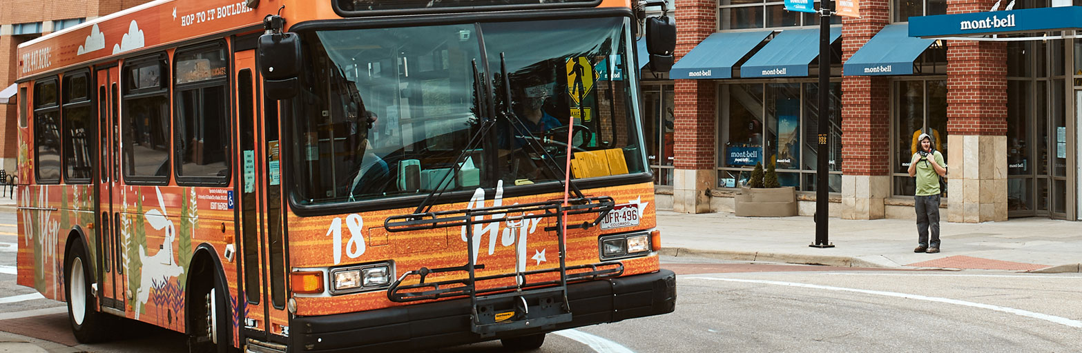 a bus on a street in boulder colorado called HOP near a store and a man on the sidewalk
