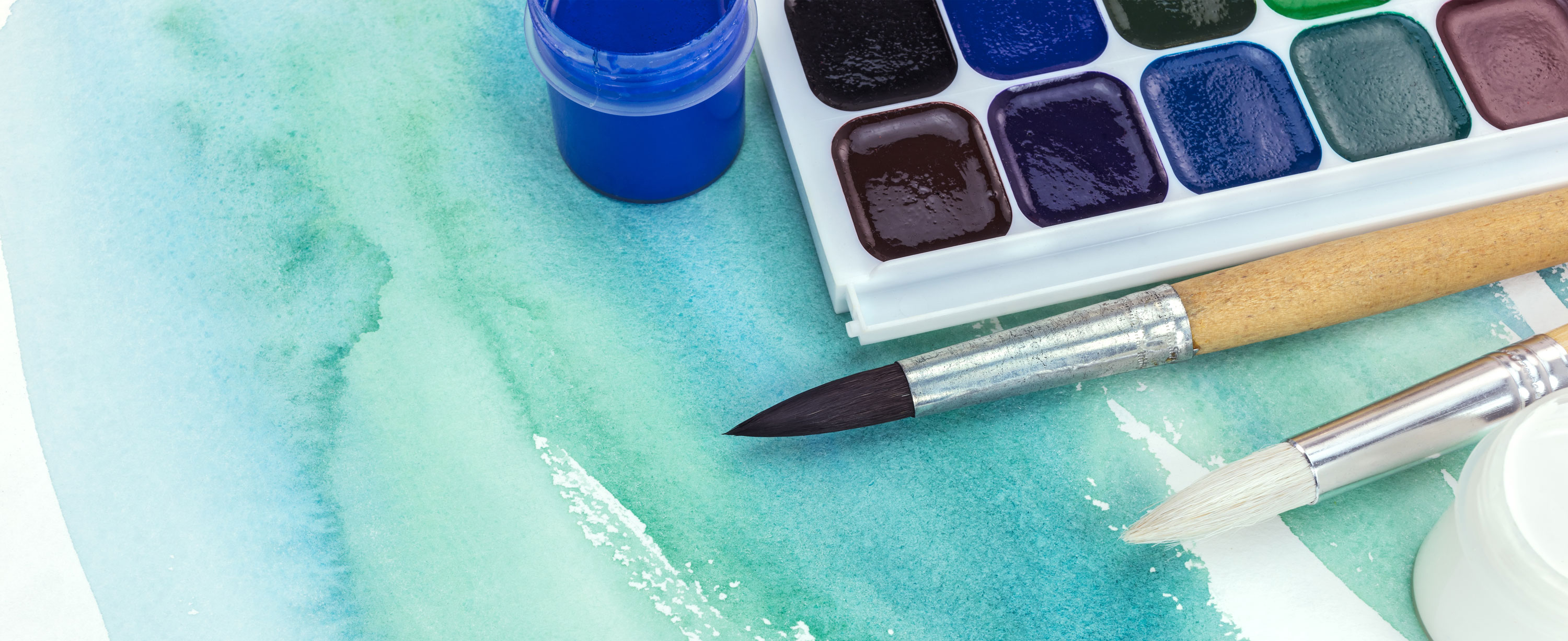 brush strokes and a paintbrush with watercolor paints in greens and blues