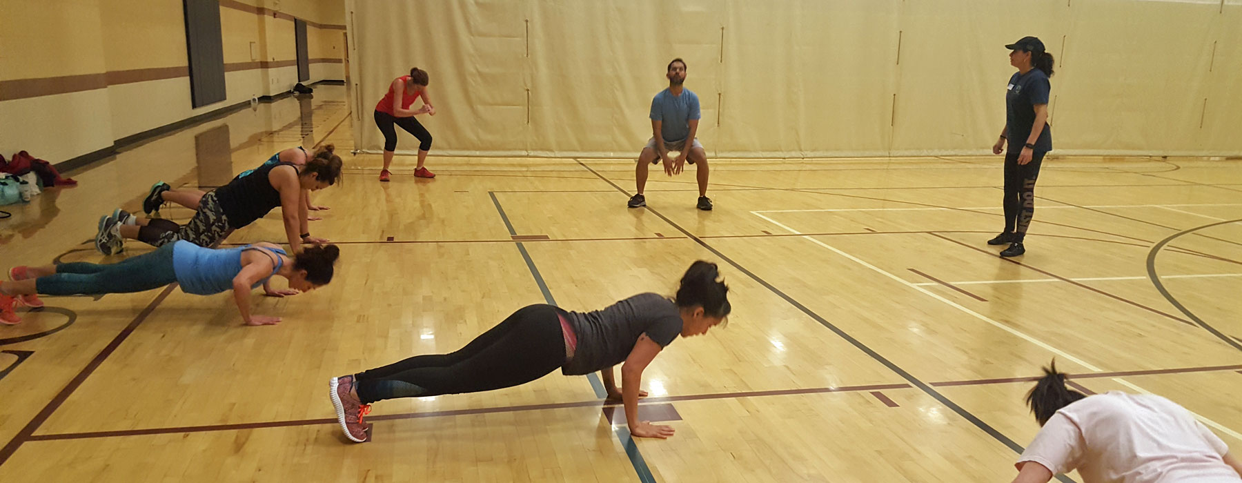 participants at boot camp class in gym doing squats and pushups