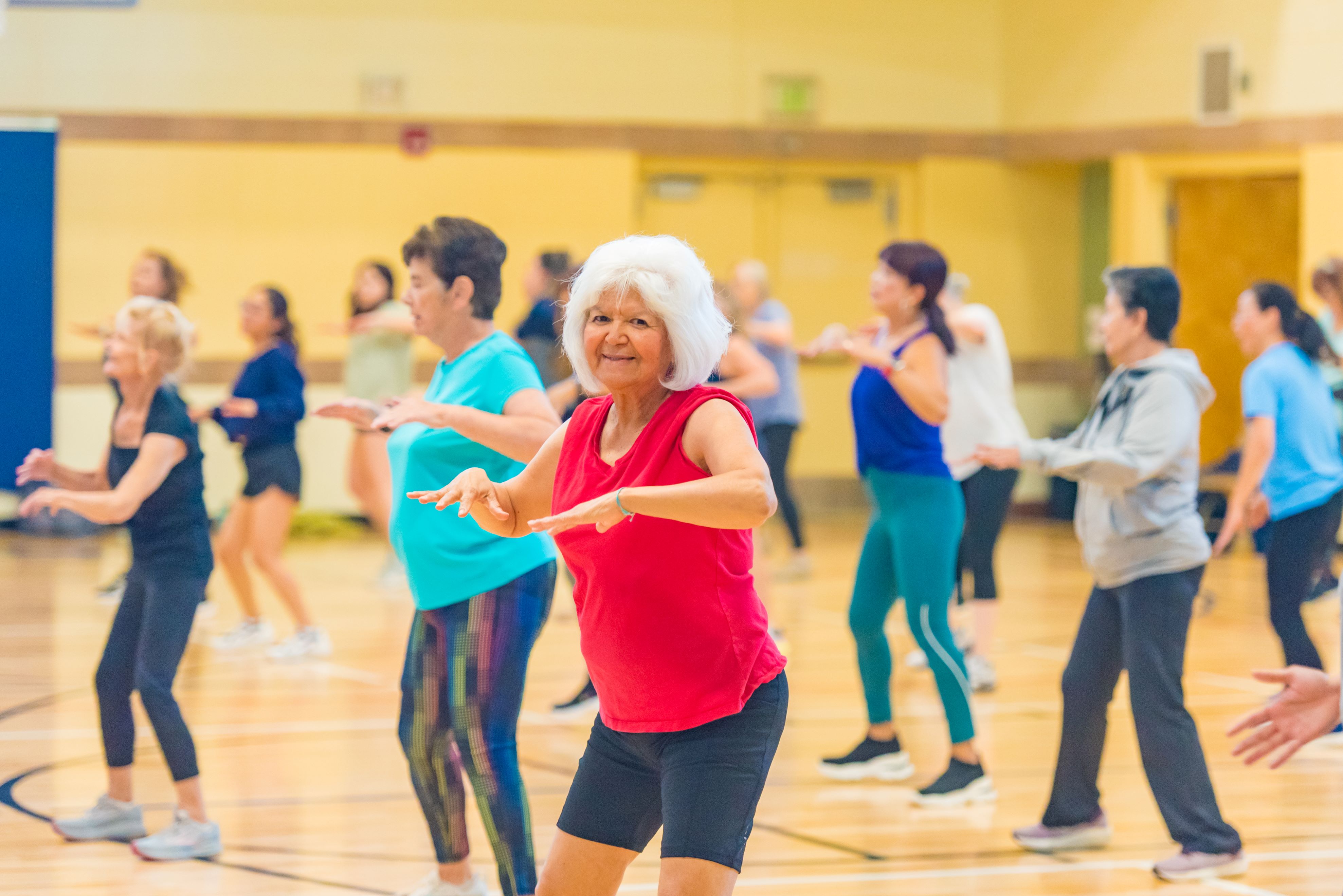 photo of a zumba class in the gym a the LRC - participant smiling and looking directly at the camera