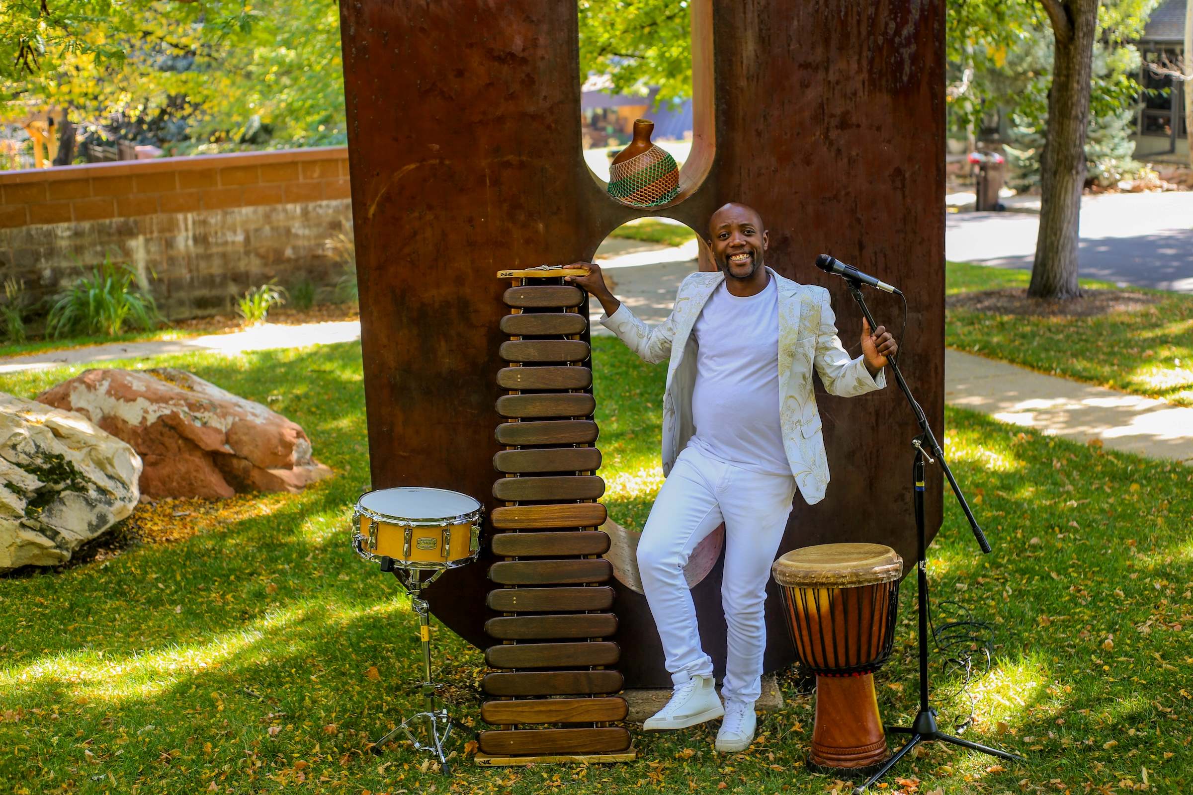 Photo of Blessing Chimanga in front of a sculpture with microphone and various other instruments staged around him.