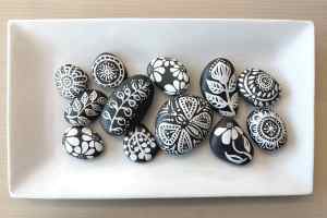 Smooth gray stones with white floral paintings on them in a variety of patterns.