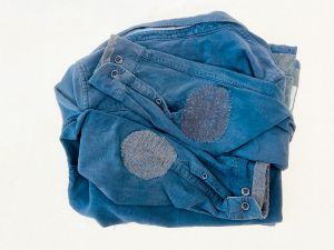 Blue jacket with visible mending (Patches and blue stitching) on the two elbows and cuffs.