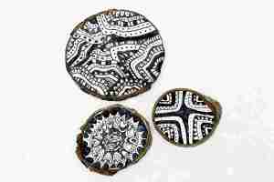 Three Zentagle drawings on wood in various black and white patterns.