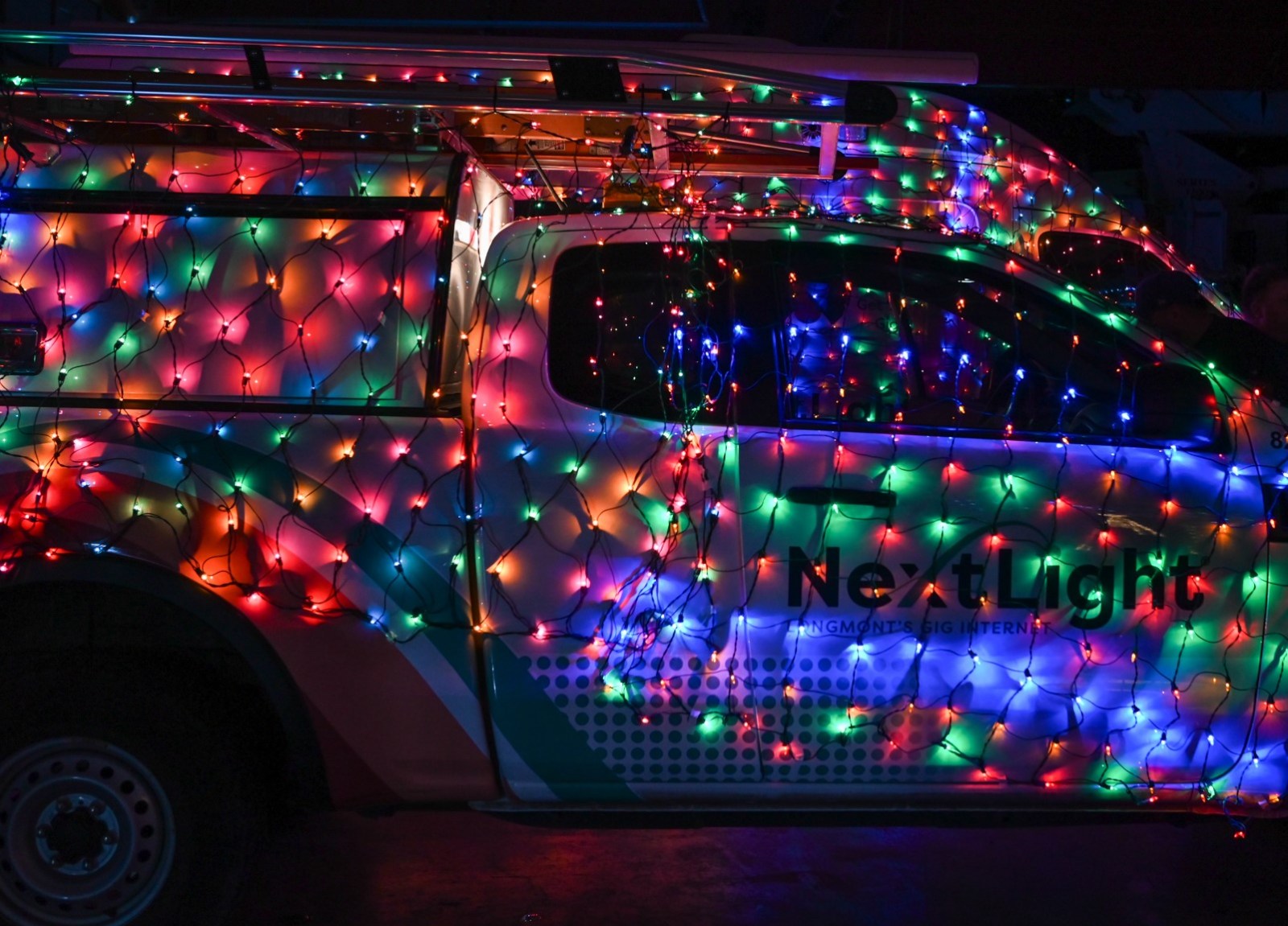 A NextLight van thoroughly decorated with multi-color Christmas lights.