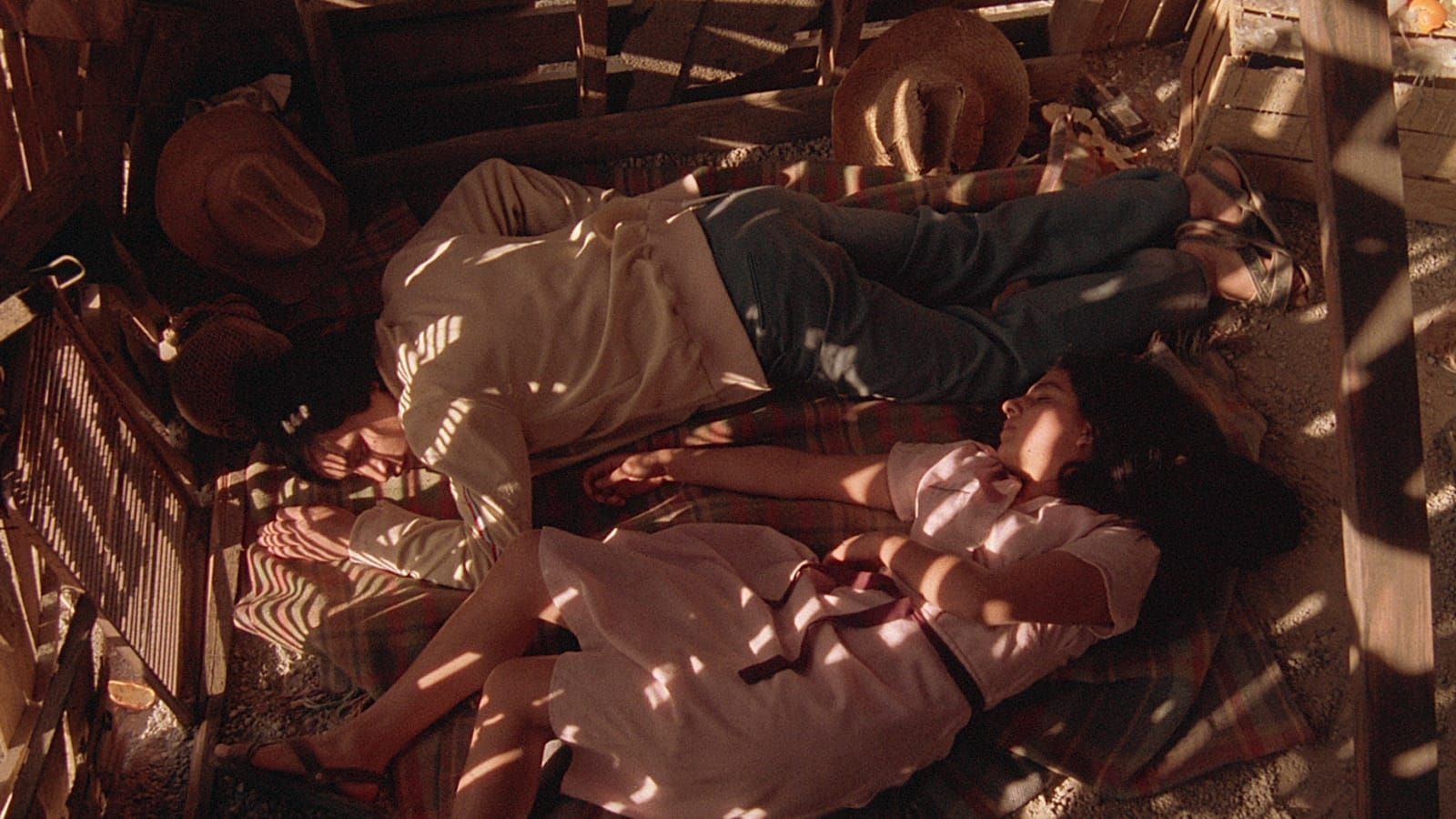 Brother and sister sleep on the gravel floor on a blanket.