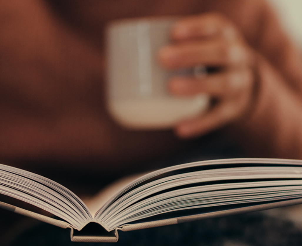 close up of a person holding a mug and reading a book