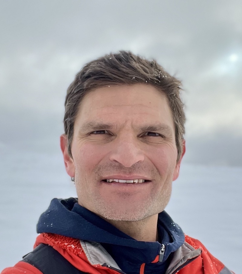 Head shot of Decon O Neil in a snowy setting wearing a coat and smiling 