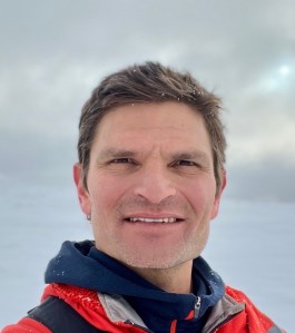 Head shot of Decon O Neil in a snowy setting wearing a coat and smiling