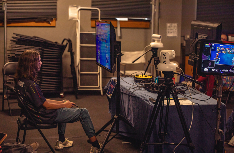 gamer sitting and playing a game in a room of gaming equipment