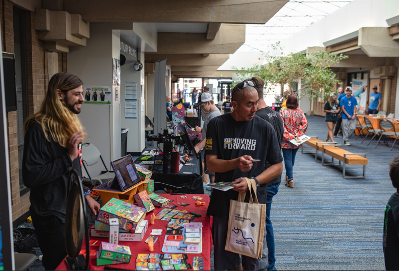 hallway with vendors and participants at booths of table top games