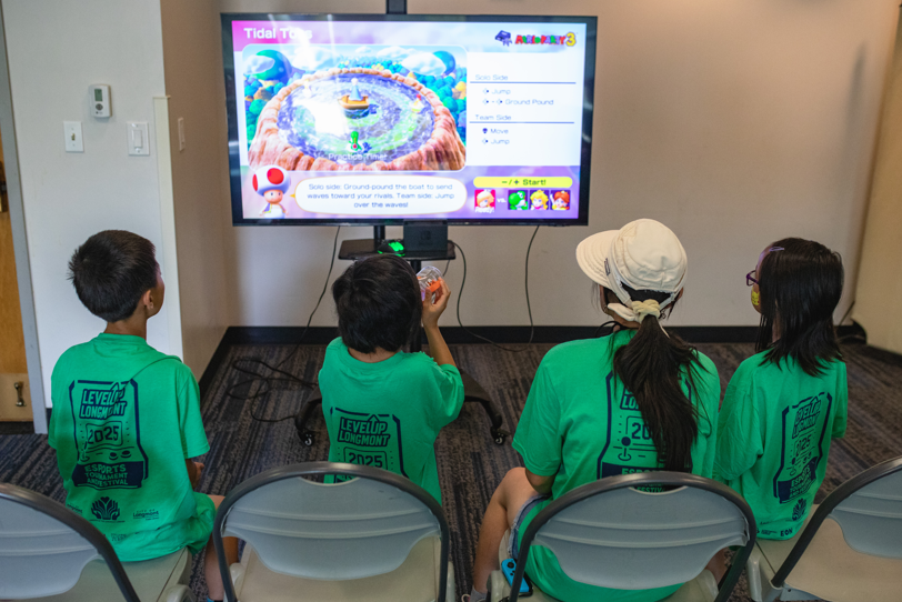 kids playing a videogame inside in front of a monitor