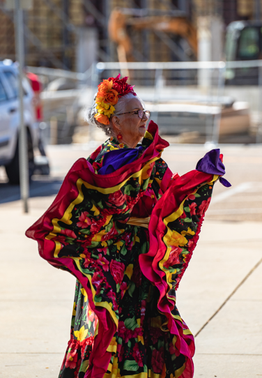 dancer with gray hair in colorful robe standing outside