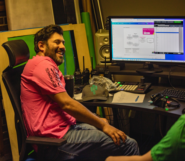 man laughing at a videogame console in front of a monitor