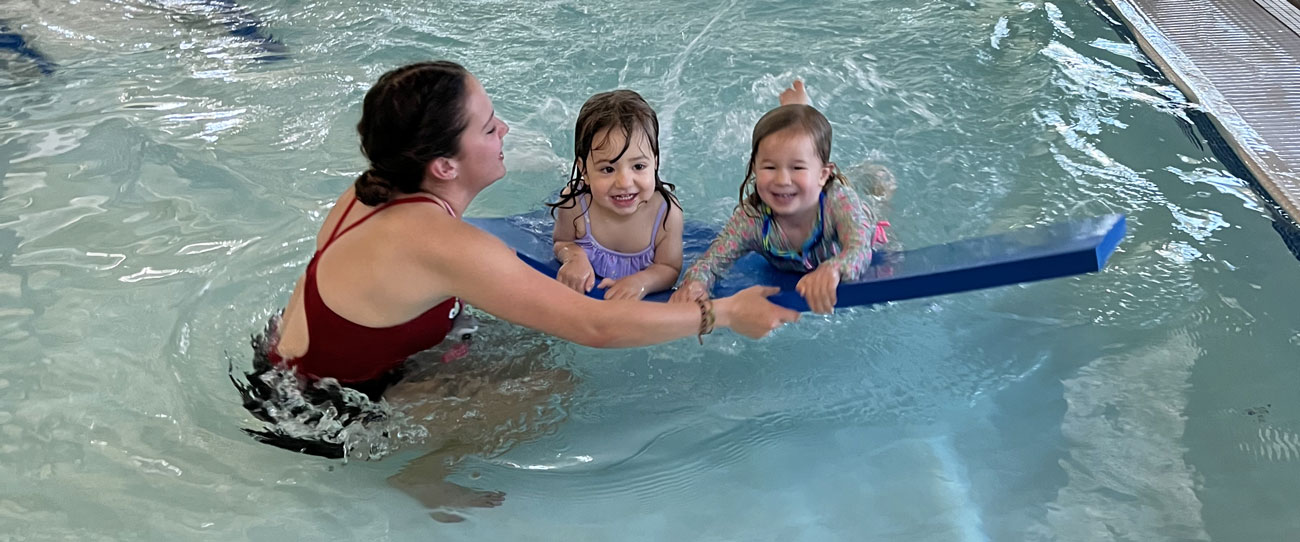 swim instructor in water teaching two young children