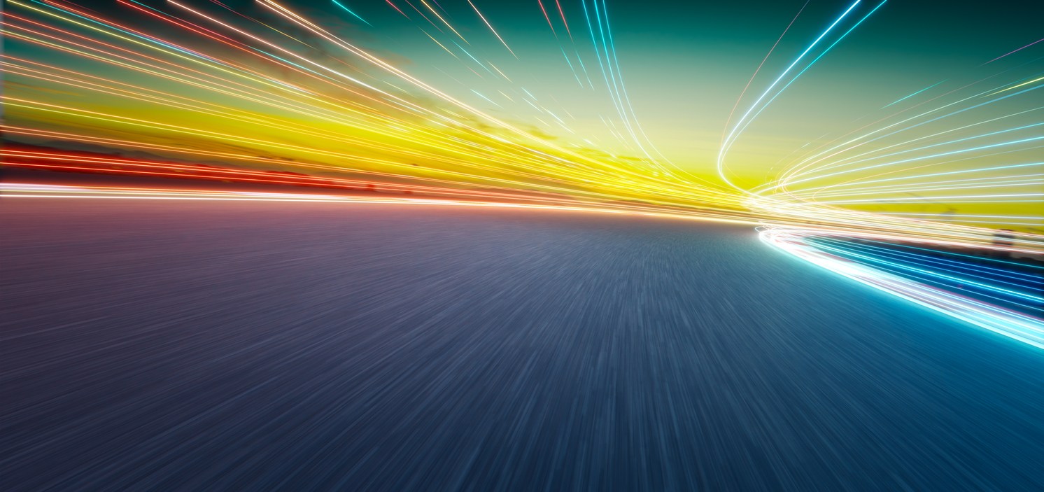 High-speed light trails around a curved track at sunset