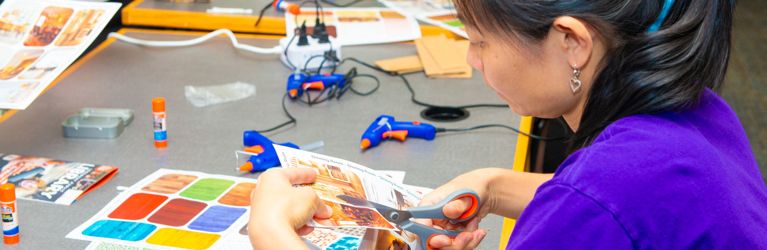 woman at a table using scissors doing crafts