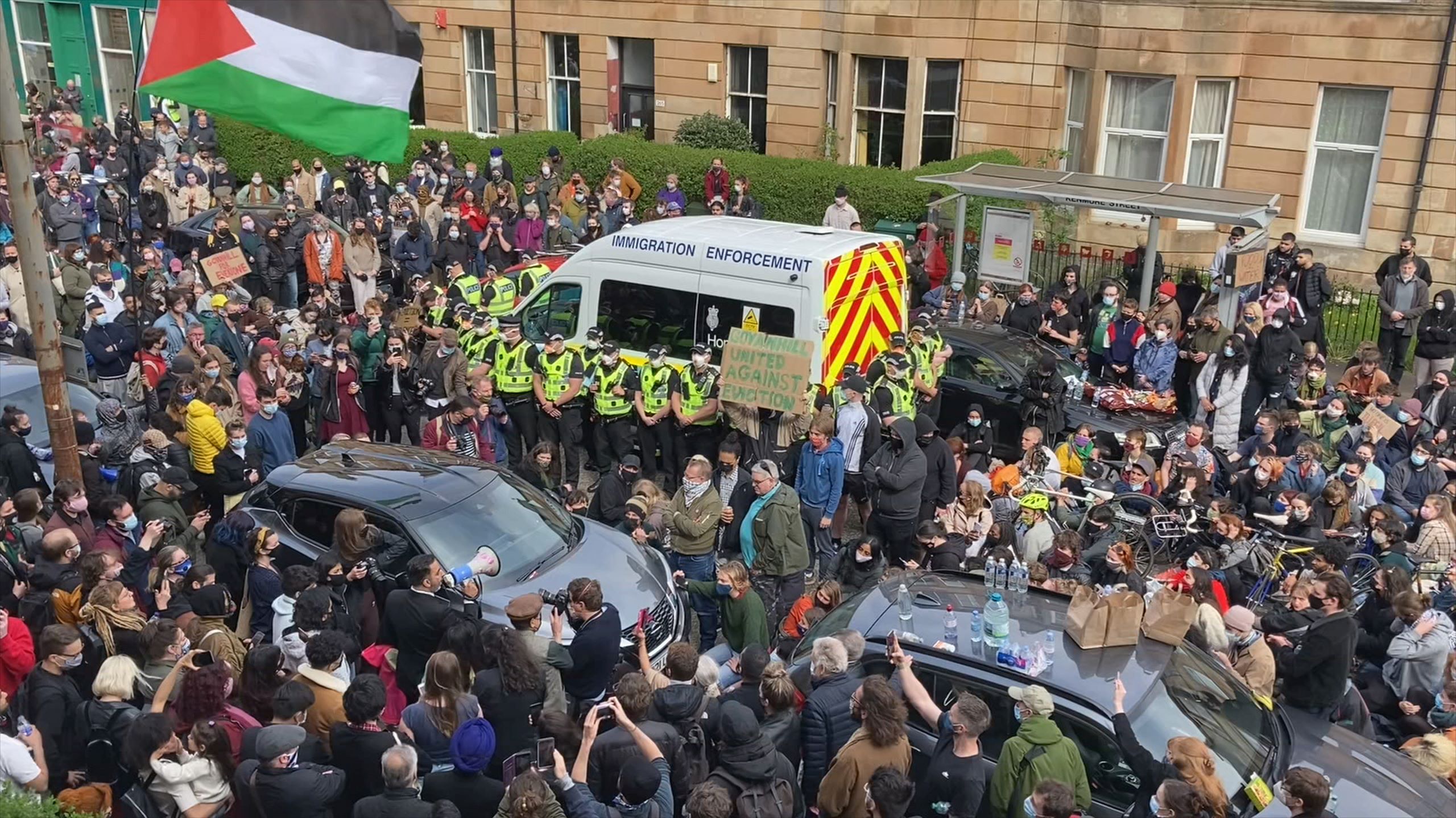 Image of hundreds of residents on Kenmure Street in Scotland flooding the street protesting the 2021 UK Home Office Immigration Raid that led to the detaining of their neighbors.