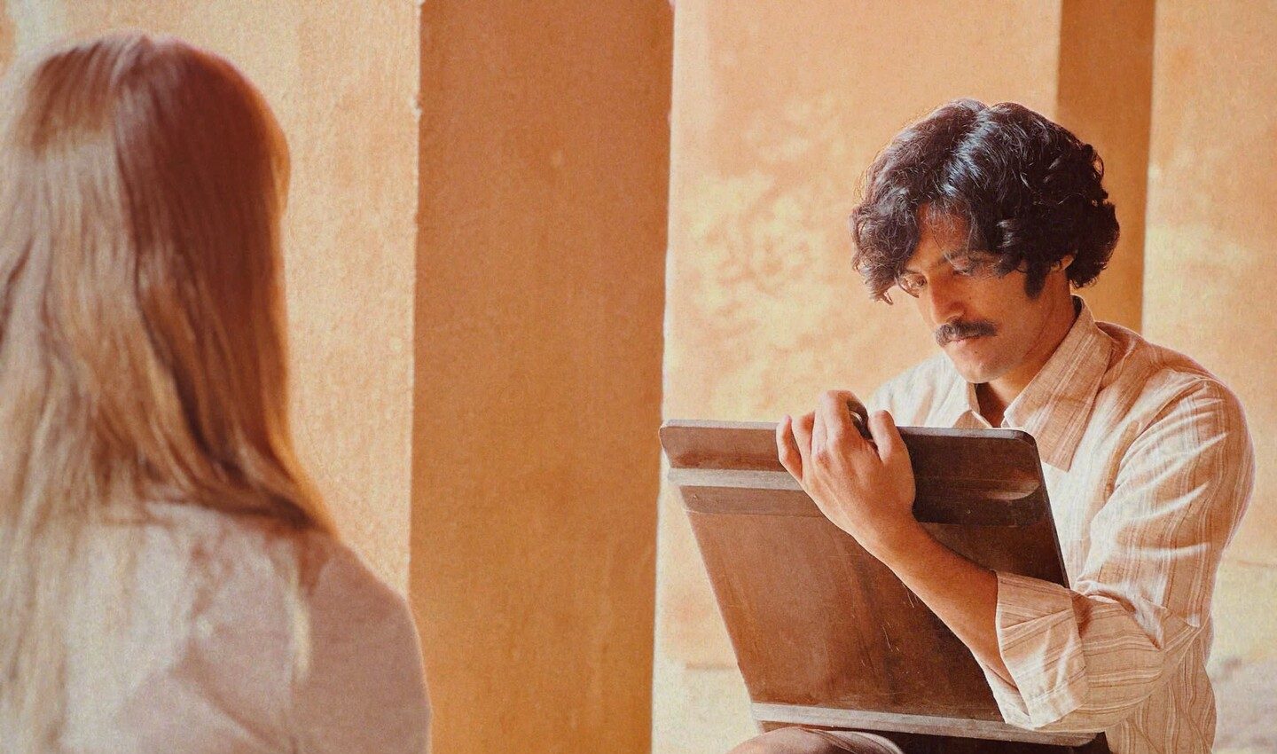 Film still from "The Cycle of Love." Man on right sketches a woman who appears posed on the left.