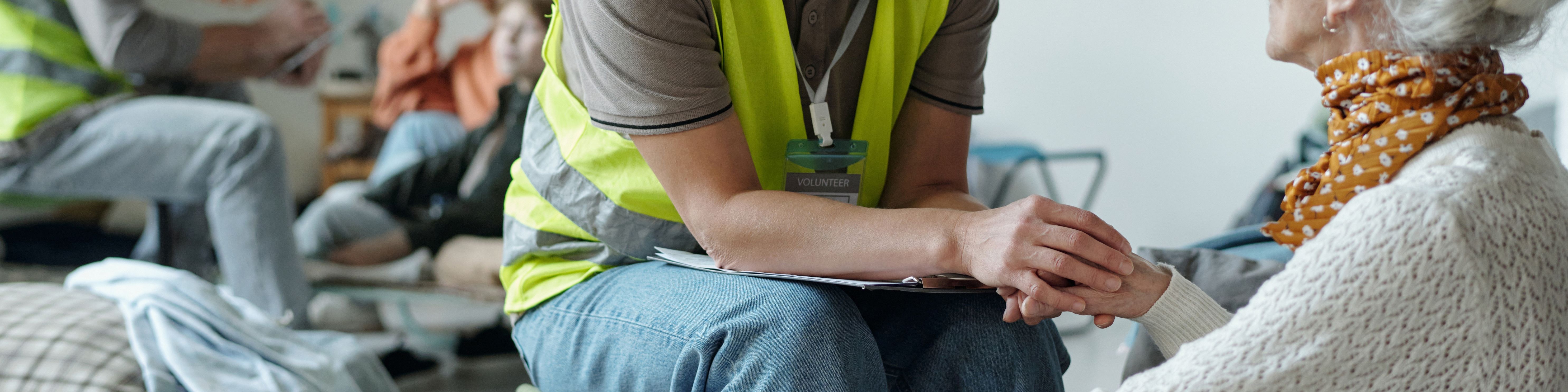 volunteer holding the hand of a guest at a homeless shelter - both faces partially out of frame