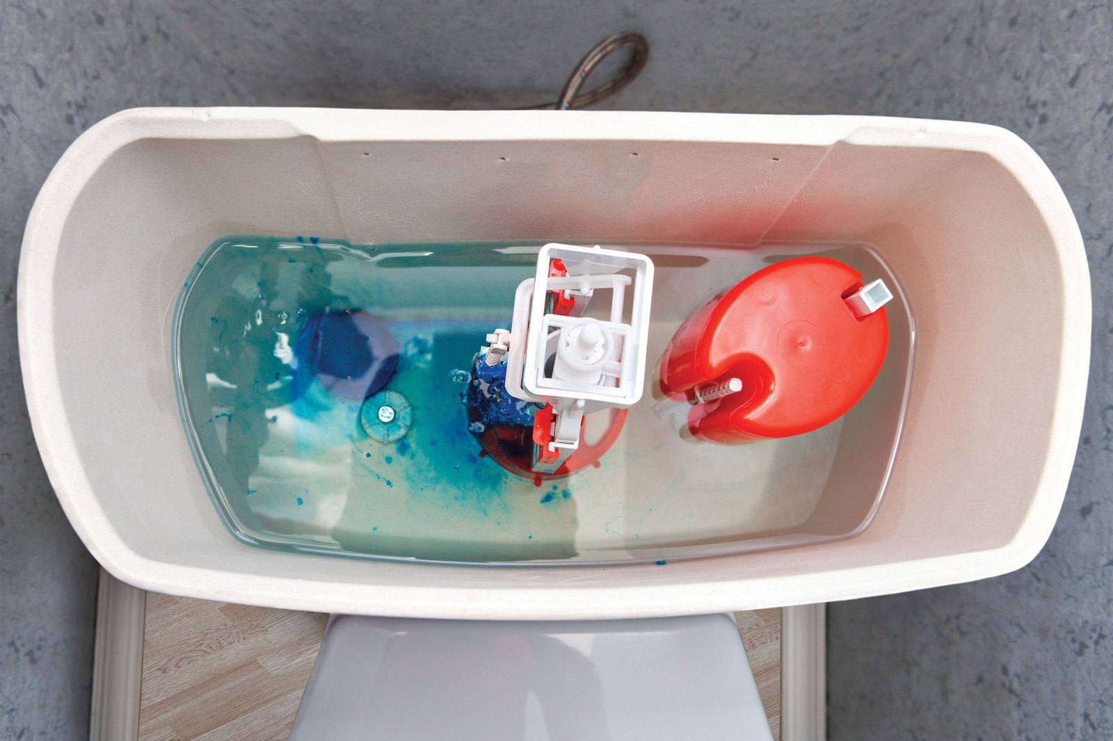 Top down view of the tank of a toilet. Blue die in the water is being used to identify a leak.