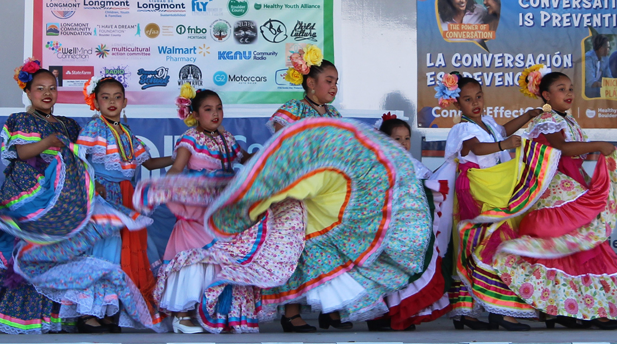Seven grade-school aged girls dance in traditional costumes in Longmont's Cinco de Mayo celebration