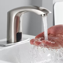 An automatic faucet with running water and a hand under the running water.