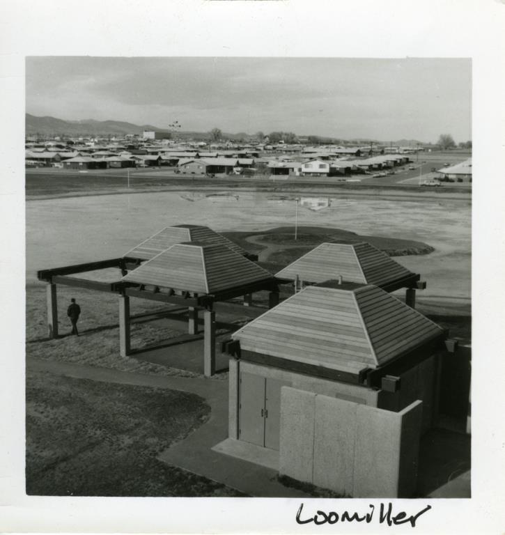 Black & white photograph of Loomiller Park looking northwest at the pump house and shelters. In the background are homes and buildings.