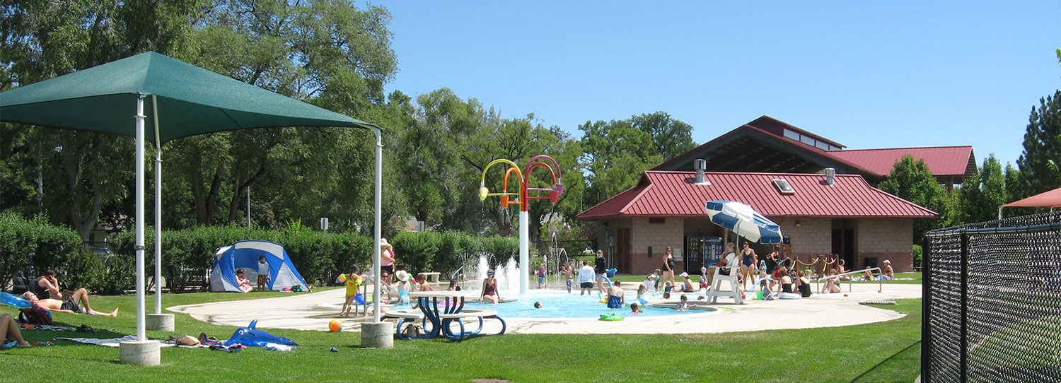 Roosevelt Activity Pool in Longmont with spray buckets umbrella shade tent picnic tables and kids splashing in water