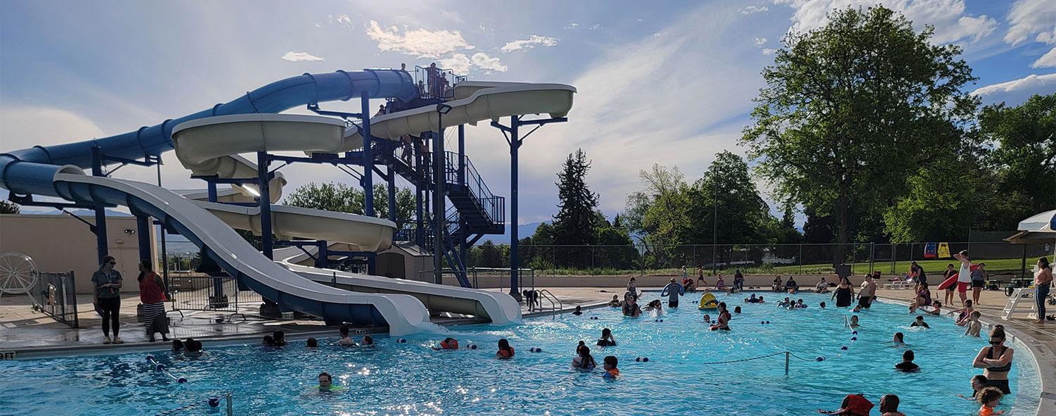 Sunset swimming pool in Longmont with slides and people swimming
