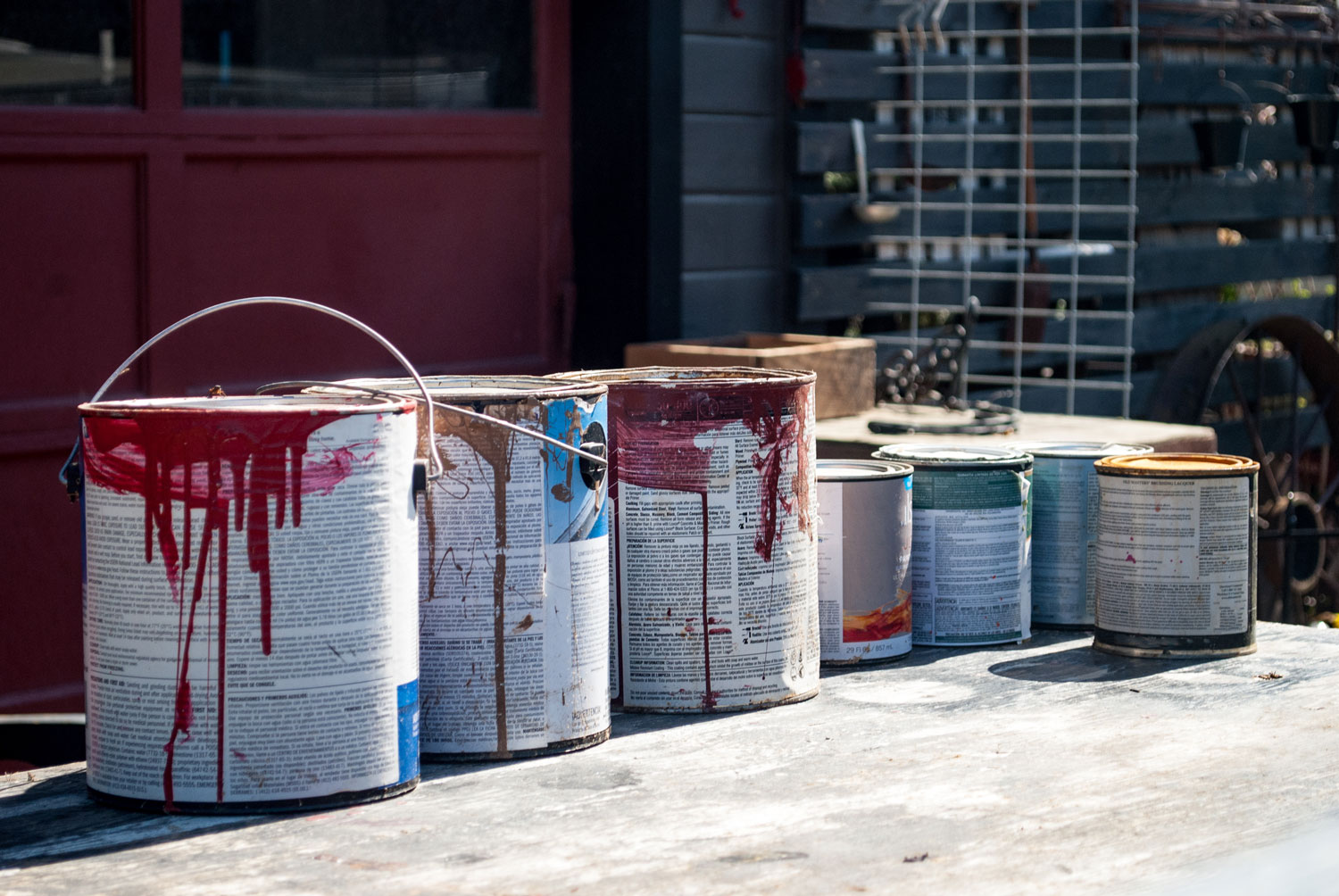 Several paint cans sit on concrete outside.