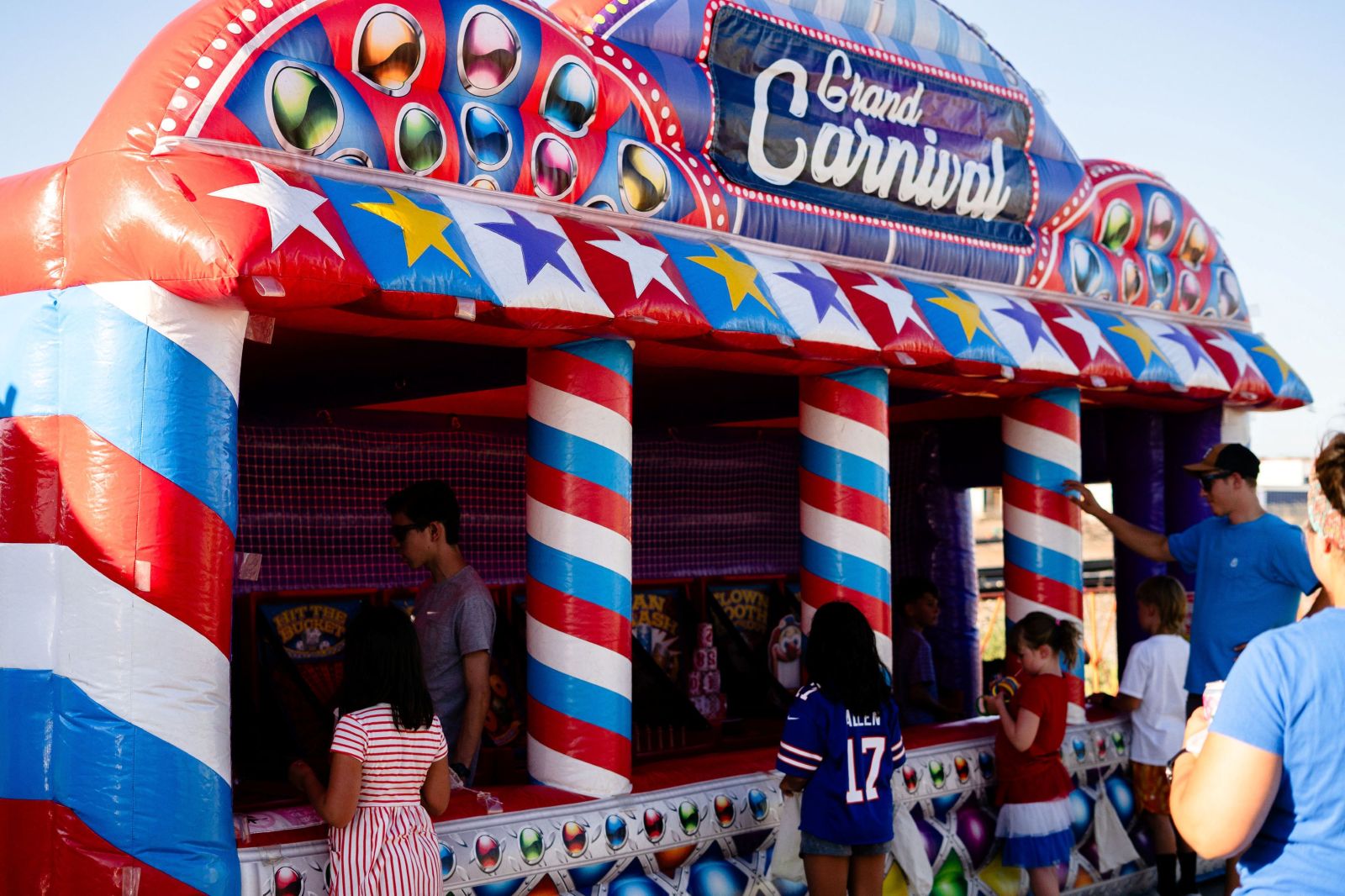 people standing around and playing at at carnival game decorated red, white and blue