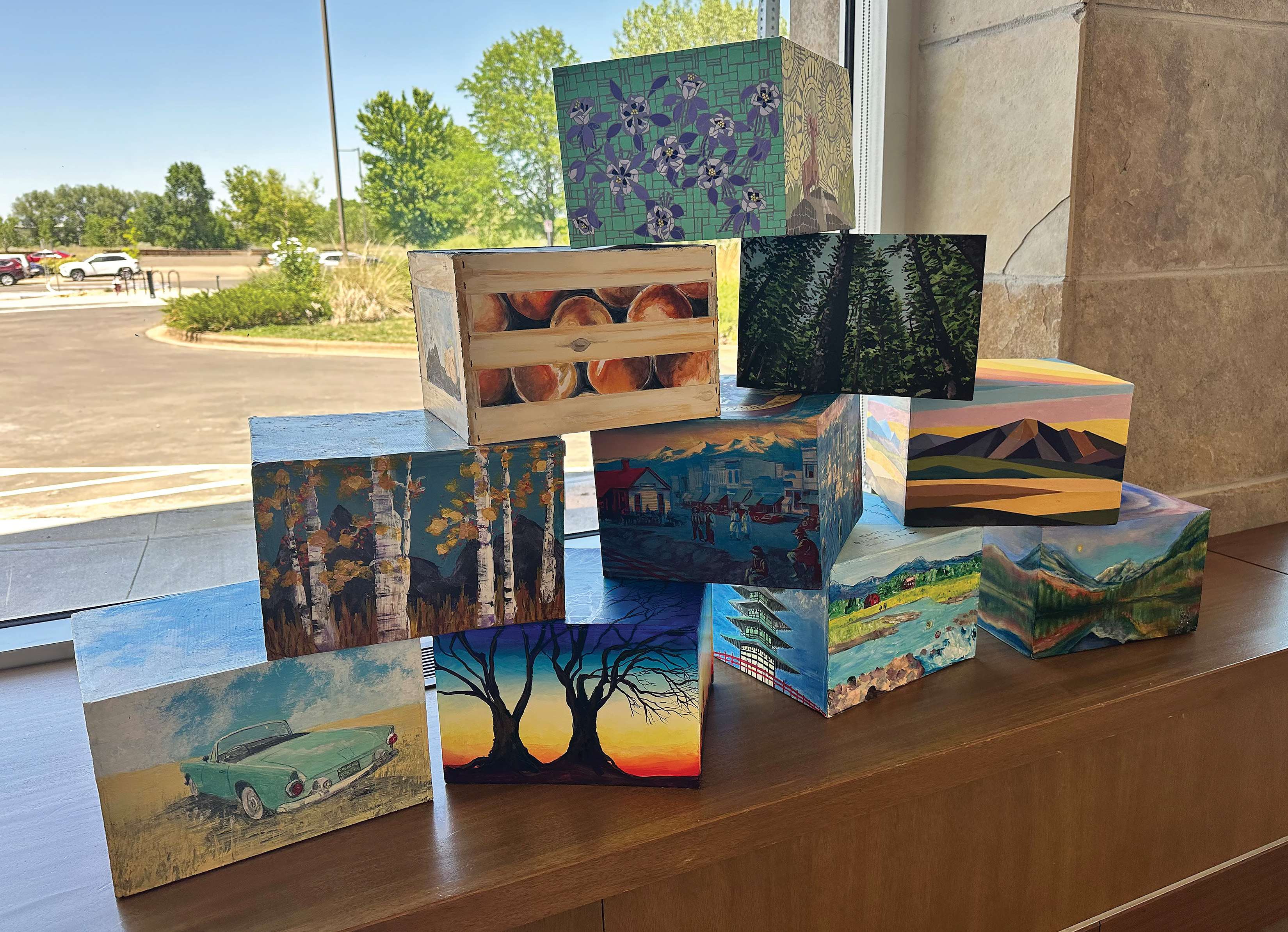 A group of 10 painted boxes sitting on a bench