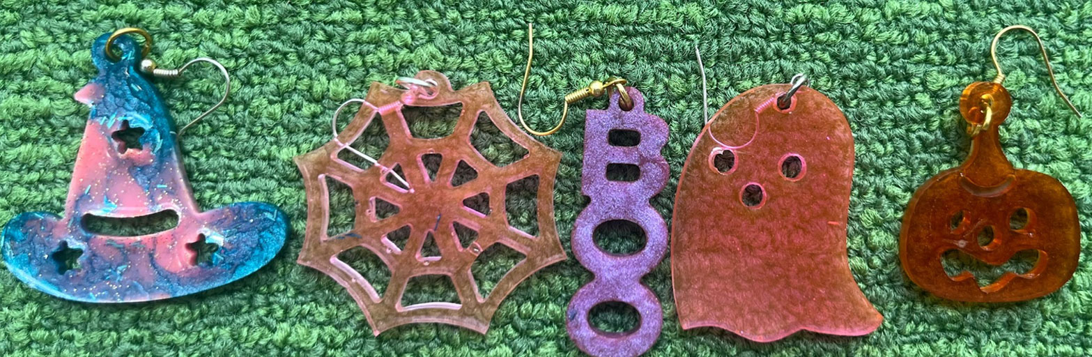 close up photo pf earrings made out of resin on a green background
