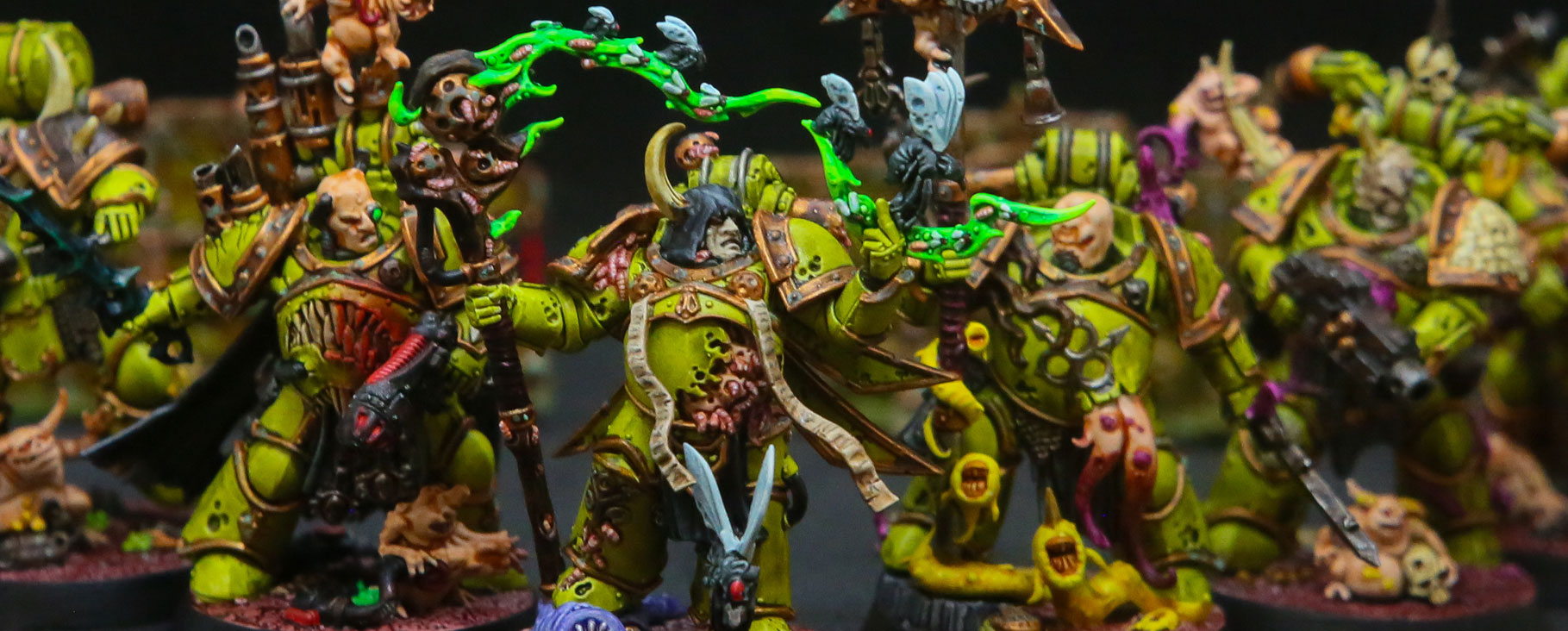 Painted Warhammer figurines lined up on a desk.
