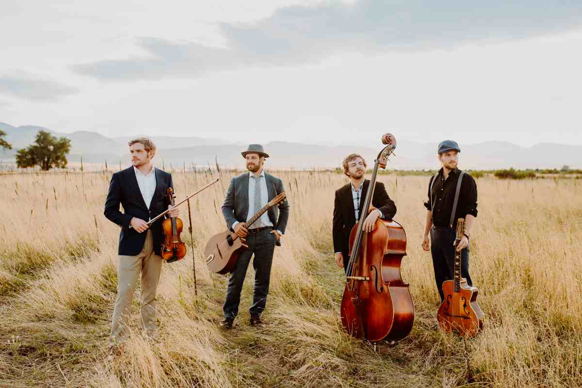 Image of LAMPOMPE band members posing with their instruments in a grass field.