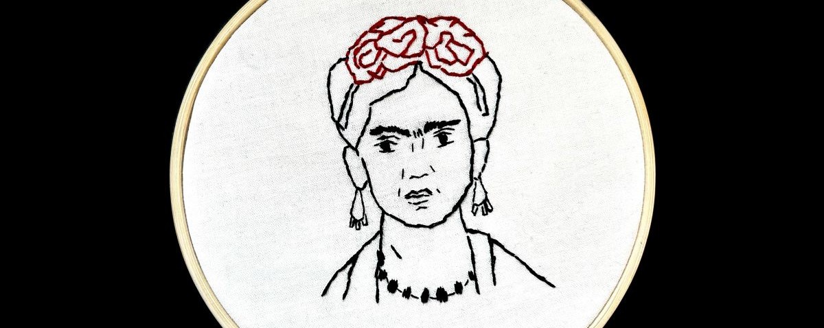 Silhouette portrait of Frida Kahlo rendered in black and red embroidery thread displayed in an embroidery hoop.