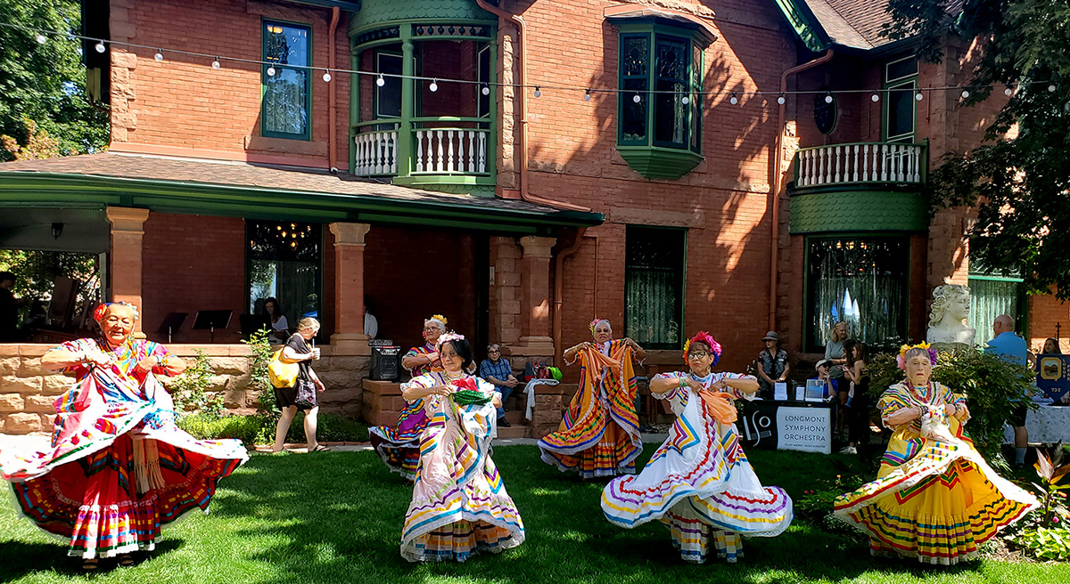 Dances in colorful traditional dresses perform in the lawn of the historic Callahan House.