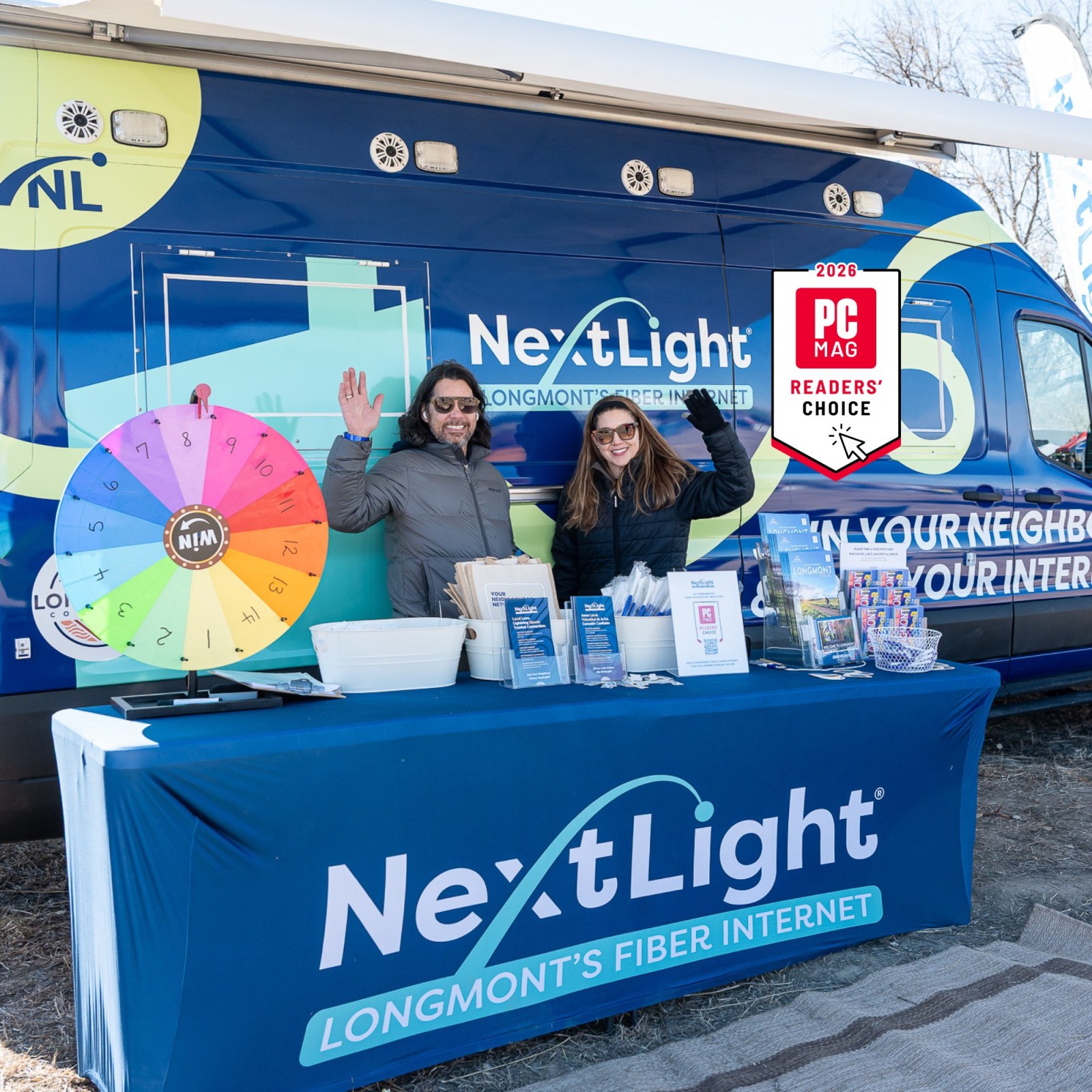 NextLight booth and van at an event with two people smiling and waving