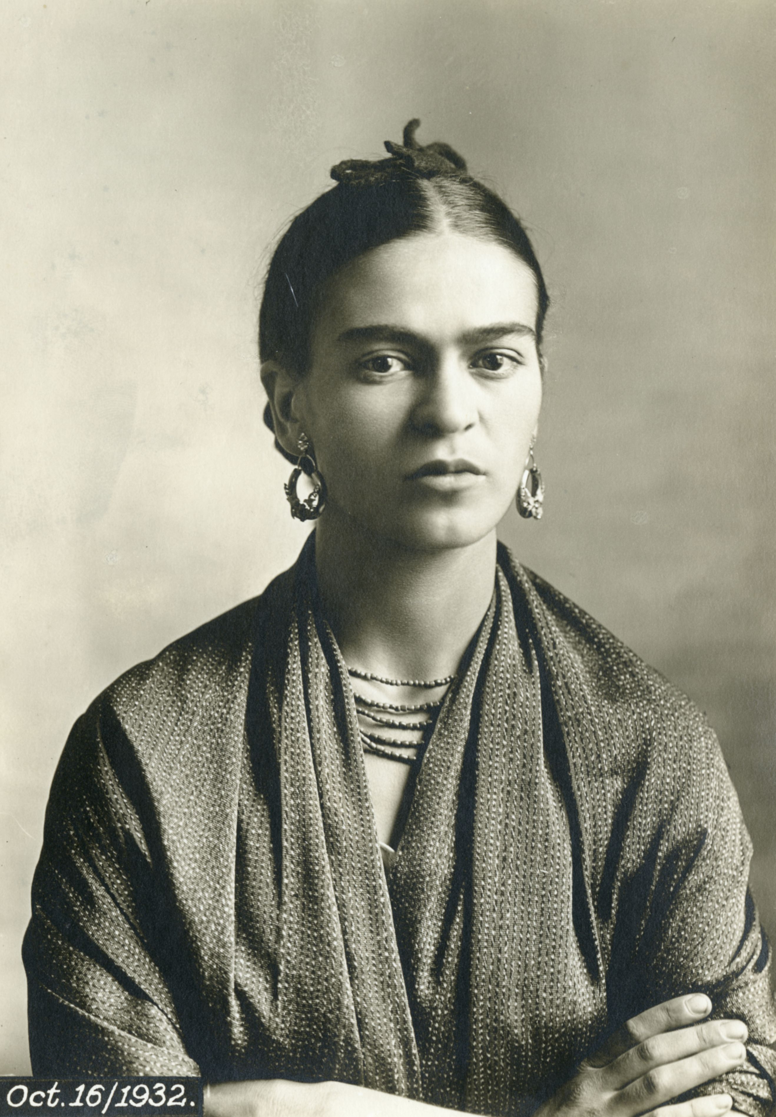 A black and white portrait of Frida Kahlo