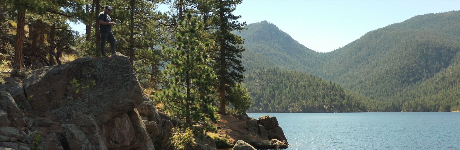 man standing on a rock overlooking the button rock preserve area and lake