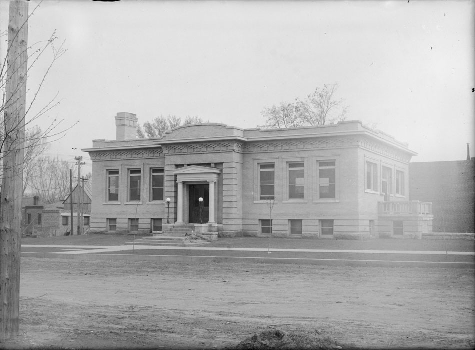Glossy black and white print of the Carnegie Library at 4th and Kimbark with a dirt road in front of the building.