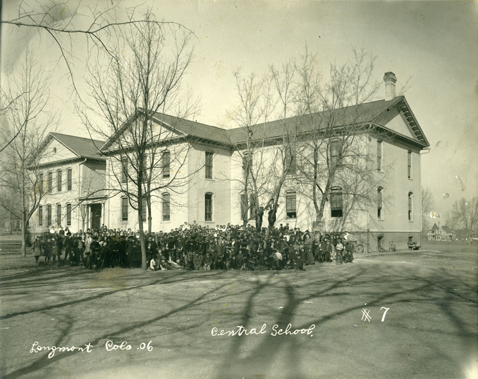 Photographic print of a group of children and teachers standing in front of Central Elementary School in Longmont. Photo taken in fall of 1906 after leaves were off trees.