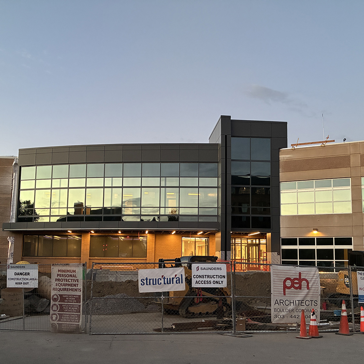 Longmont's Safety & Justice Center is pictured near completion. The building has a new north entrance with a glass wall, but is still surrounded by construction fencing and signage.