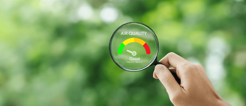 magnifying glass with a scale of air quality levels against a green background.