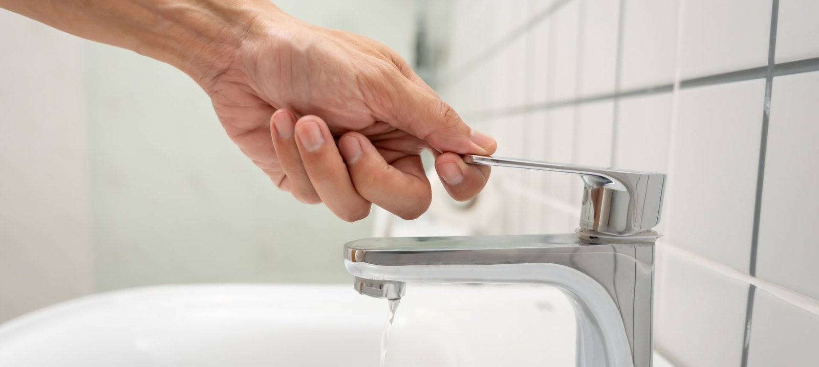 A person turning off a faucet of running water.