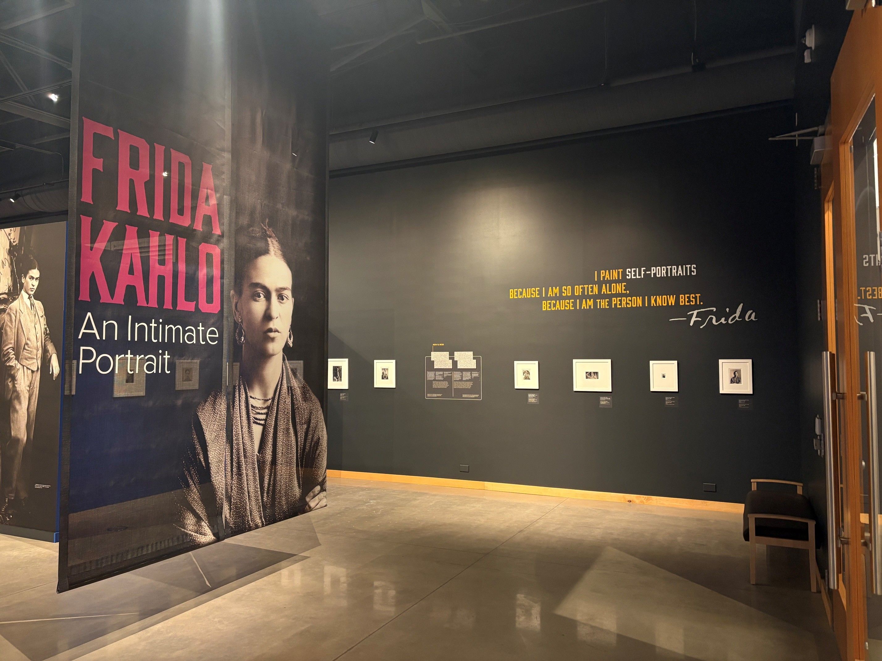 A gallery of a museum with a Frida Kahlo graphic along the wall