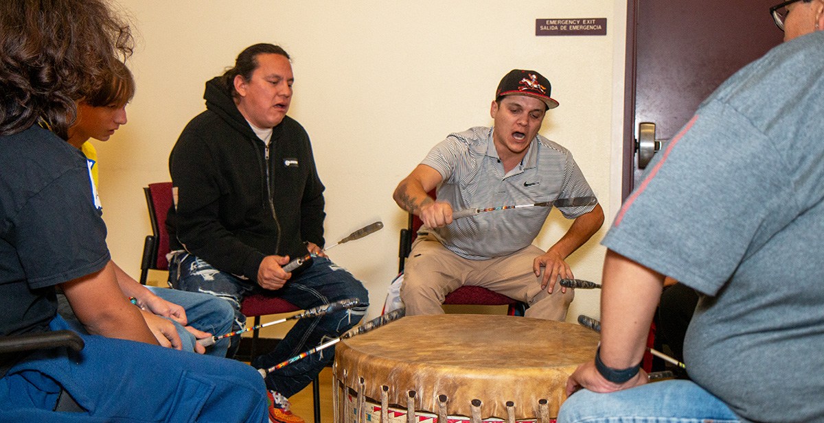 Five men play a Native American drum.